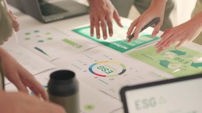 A team engages in a detailed discussion over documents related to ESG targets, circular economy, and sustainability strategies. - Powered by Shutterstock - Get 15% off with code: PIKWIZARD15