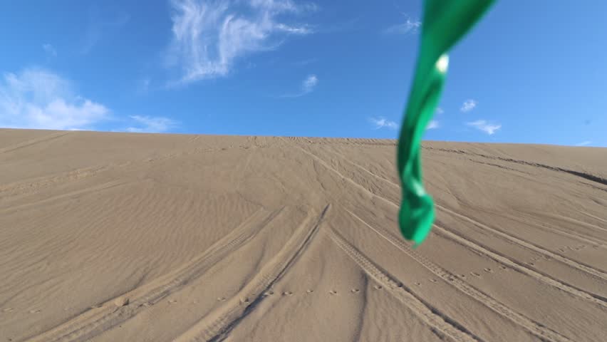 Motor-biker riding across sand dunes slow motion push in shot