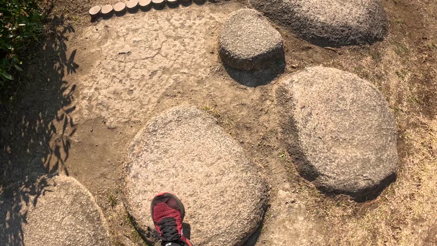Person walking over stepping stones in a serene garden