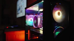 Dark room with a gaming computer with a transparent side panel revealing internal components with RGB lighting and a monitor in the distance. - Powered by Shutterstock - Get 15% off with code: PIKWIZARD15