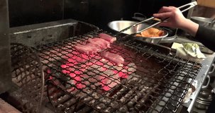 A cook grills beef tongue over charcoal in the kitchen of a restaurant in Japan.