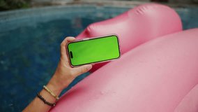 POV male hand holding smartphone with empty green screen chroma key relaxing near pool with pink flamingo background  - Powered by Shutterstock - Get 15% off with code: PIKWIZARD15