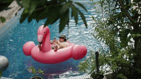 Man use phone on inflatable pink flamingo float mattress on pool party.  - Powered by Shutterstock - Get 15% off with code: PIKWIZARD15