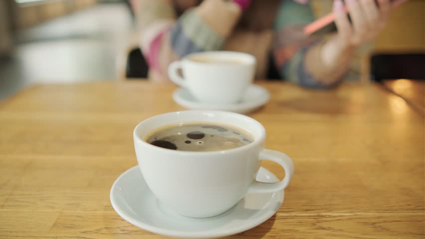 Two cups of coffee resting on a wooden table, representing a cozy coffee break moment in a comfortable setting. Royalty-Free Stock Footage #3462118417