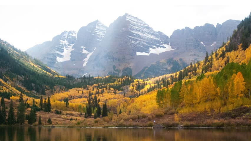 Maroon Bells Pyramid Peak Aspen Snowmass Colorado wilderness Incredible stunning cinematic aerial drone fall autumn colors snow covered Rocky Mountains peaks morning backward motion
