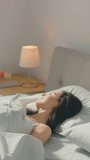 Beautiful Brunette Slowly Waking up in the Morning, Stretches and Gets Up from the Bed, Sun Shines on Her From the Big Window. Video Footage with Vertical Screen Orientation 9:16