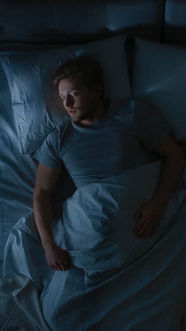 Top View of Handsome Young Man Sleeping Cozily on a Bed in His Bedroom at Night. Video Footage with Vertical Screen Orientation 9:16 Royalty-Free Stock Footage #3462148911