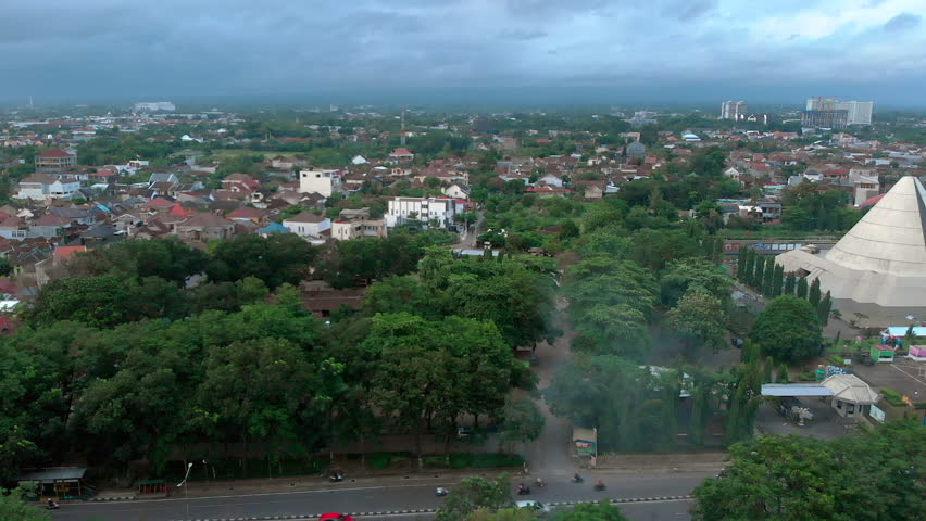 Aerial footage Yogyakarta museum monument building showing conical shape design surrounded by outdoor water park, called MONJALI park