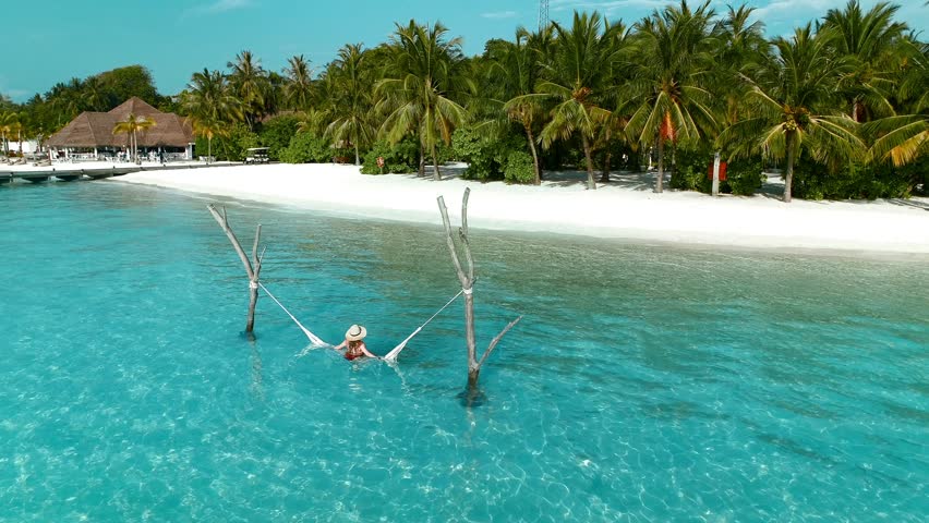 Aerial view of beautiful Maldives with woman relaxing in hammock, Laccadive Sea.