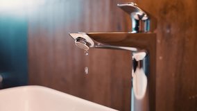 close-up shot chrome plated trendy leaking faucet water dripping into sink, broken leaking plumbing tap. drops of water dripping from spout of water faucet. leaky faucet valve. waste of water concept. - Powered by Shutterstock - Get 15% off with code: PIKWIZARD15