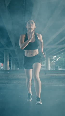 Close Up Portrait Shot of a Beautiful Confident Fitness Girl in Black Athletic Top and Shorts Jogging. She is Running in Urban Environment. Video Footage with Vertical Screen Orientation Royalty-Free Stock Footage #3462297387