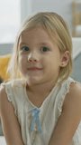 Portrait of Sweet Cute Happy Young Blonde Girl Smiling on Camera. In the Background Blurred Sunny Room. Video Footage with Vertical Screen Orientation 9:16