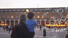 Happy childhood. Fun boy enjoy soap bubbles performance. Colorful fly show. Joyful child catch lot foam circles. Public place performer. Urban holiday square. Kid play city street. Entertainment event - Powered by Shutterstock - Get 15% off with code: PIKWIZARD15
