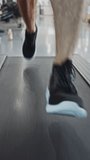 Athletic Muscular Man Running on a Treadmill, Leg and Cardio Day. Strong Man Training in the Modern Gym. Front View of Low Ground Shot. Focus on Legs. Vertical Screen Orientation Video 9:16