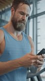 Muscular Heavyweight Champion Walks Through Gym, Uses Smartphone for Social Media and Conducting Business Affairs. Vertical Screen Orientation Video 9:16