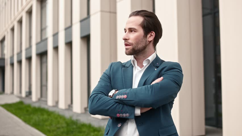 Confident business man wearing blue suit. Male company director posing with crossed arms. Male executive director wearing business clothing. Serious bearded office worker in official outlook.