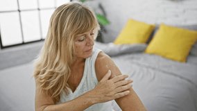 Cheerful middle age blonde woman happily applying skin treatment on arm, comfortably resting in bed inside cozy bedroom - Powered by Shutterstock - Get 15% off with code: PIKWIZARD15