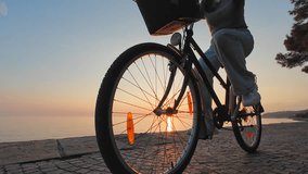 Medium low angle tracking shot of a teenage girl riding her bike on a coastal path in the city as the sun is setting in the background - Powered by Shutterstock - Get 15% off with code: PIKWIZARD15