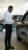 Preparing all info needed. African american salesman manager conducts inventory of new cars. Vertical video