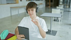 Young caucasian male student with headphones using tablet in modern university library - Powered by Shutterstock - Get 15% off with code: PIKWIZARD15
