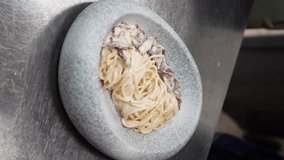 Chef prepares and serves fresh pasta with sauce, man prepares traditional Italian dinner in restaurant kitchen, delicious food, haute cuisine. vertical video