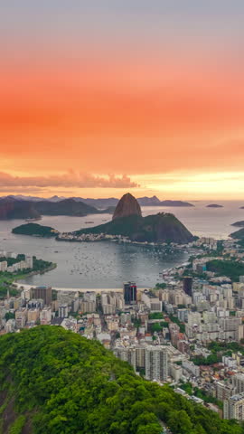 View of sunset on Rio De Janeiro looking towards Sugarloaf Mountain and the Atlantic ocean, Brazil. Aerial vertical drone hyperlapse.