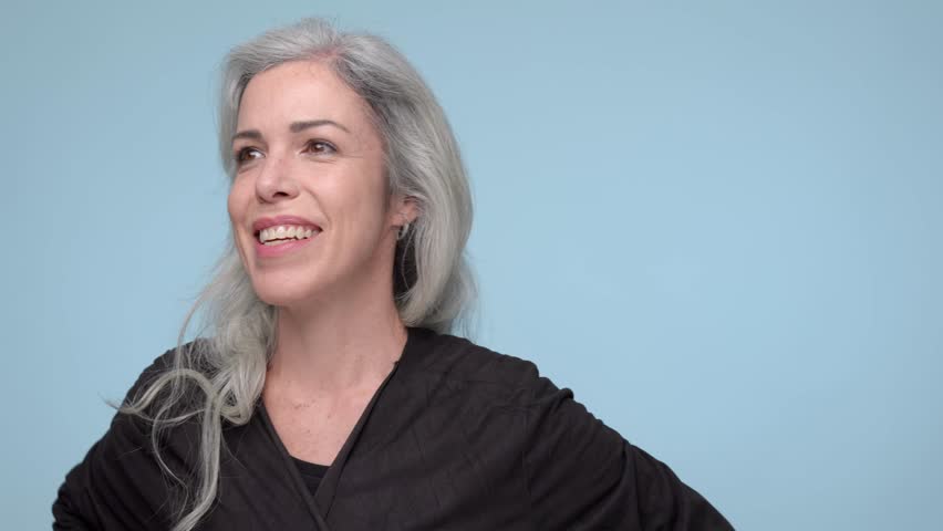 A smiling woman with gray hair looking to the side with a cheerful expression.