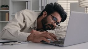 Tired sleepy exhausted Arabian Indian business man drowsy frustrated businessman worker employee sad fatigued lazy male guy sleep sleeping at office desk with laptop boring computer work overwork nap - Powered by Shutterstock - Get 15% off with code: PIKWIZARD15