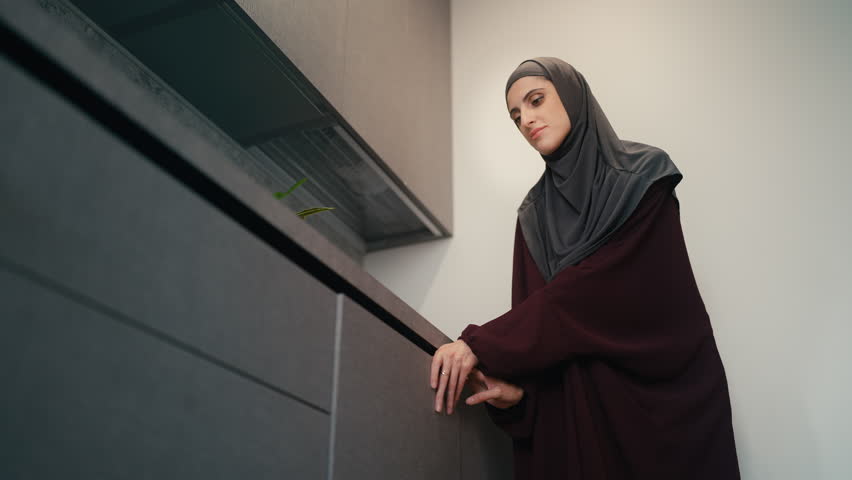 Happy Muslim housewife unloading dishwasher, admiring crystal clear glass