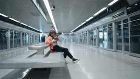 Black female with vitiligo skin, attentively using smartphone while sitting on subway station. Young woman focus on messaging or browsing, enjoying using technology with 5G fast internet connection 