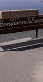 Portrait footage of the town of Benidorm in Spain showing a park bench and the view from the northern side of the town in the summer time.