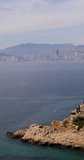 Portrait footage of the town of Benidorm in Spain showing the rocky front and the view from the northern side of the town in the summer time.