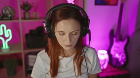 Young adult redhead woman wearing headphones surrounded by neon lights in a modern gaming room at home