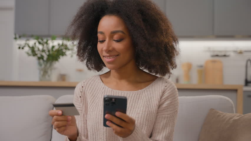 African American woman girl use mobile phone ethnic female customer buyer order online delivery at home paying money successful online payment shopping with credit bank card and smartphone happy smile Royalty-Free Stock Footage #3462660451