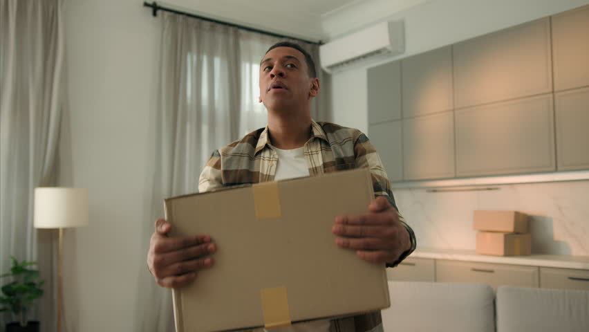 Tired displeased sad African American man home owner difficult move to new apartment own house with cardboard boxes delivery exhausted fatigued male guy carry parcel relocating hard moving day fatigue Royalty-Free Stock Footage #3462662713