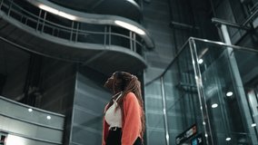 Young African woman with braided hair looking up, marveling at modern architectural structure. Females expression suggests reflection or inspiration, capturing sense of discovery and admiration - Powered by Shutterstock - Get 15% off with code: PIKWIZARD15