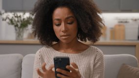 Shocked sad girl African American woman on sofa hold smartphone looking at mobile phone screen worried read bad news failure negative result rejection bank debt cellphone connection problem at home - Powered by Shutterstock - Get 15% off with code: PIKWIZARD15