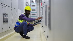 4K African man engineer in safety uniform working on tablet in industry factory server electric control panel room. Industrial technician worker maintenance power system at manufacturing plant room. - Powered by Shutterstock - Get 15% off with code: PIKWIZARD15