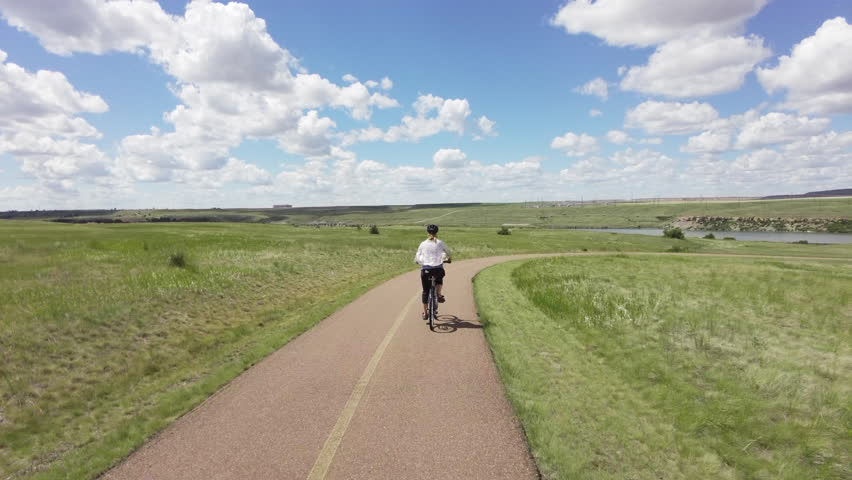 Woman rides bike on paved trail near river in Great Falls