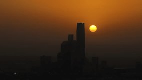 Drone shot of sunset behind silhouette buildings of KAFD in Riyadh, Saudi Arabia