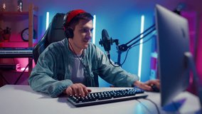 Young hipster man playing online computer video game, colorful lighting broadcast streaming live home. Ecstatic celebration winning match. Gamer lifestyle, E-Sport online gaming technology concept