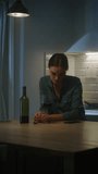 Lonely Young Woman Drinking from a Wine Glass in the Dark Kitchen. Depressed and Sad Adult Girl with Alcohol Problem Drinks Alone, Bad Relationships, Work Stress, Other Problems. Vertical Screen
