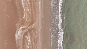 Sea beach aerial view. Top view of the beach with the waves of the sea crashing onto the shore. High angle video clip natural view, for use as a background for relaxation, travel. Footage holiday 