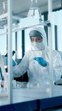 Beautiful Female Medical Scientist Wearing Coverall and Face Mask Using Micro Pipette while Working with Test Tubes. Vaccine, Drugs Research and  Development Laboratory. Vertical Screen Video