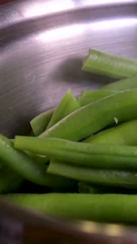 A close-up view of vibrant green beans starting to boil in a steaming pot. Cooking vegetarian and healthy eating concept.
