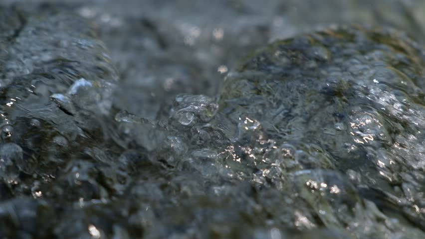 Blurred on backgroud.On top water flows in a stream where air bubbles form.