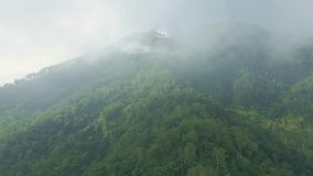 Drone fly over the cloudy fog haze of the rainforest of indonesia. Mountain forest view of rural landscape.