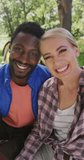 Vertical video of portrait of happy diverse couple camping in park, slow motion. Nature, hiking and park concept.