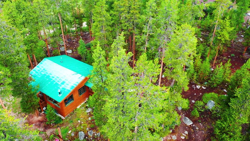 Drone Descending into Cabin in the Woods Isolated and Hidden in Aspen Tree Grove Forest next to Hiking Trail with Large Rocks or Boulders. Aerial View