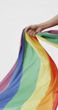 Vertical video of hand of caucasian woman holding rainbow fabric. Gender, lgbt, queer, gay pride and equality concept.